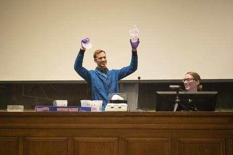 Man presenting an experiment in a large lecture hall