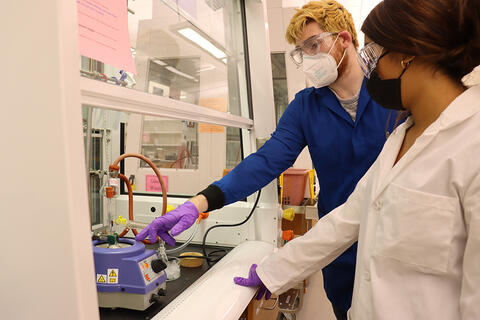 Man and woman in labs coats near chemical fume hood