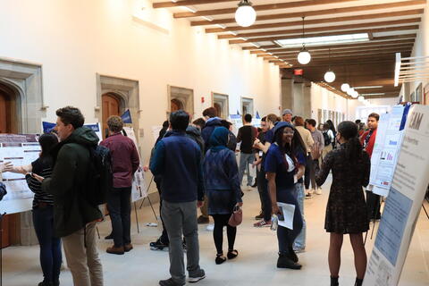 people standing in hallway lined with research posters