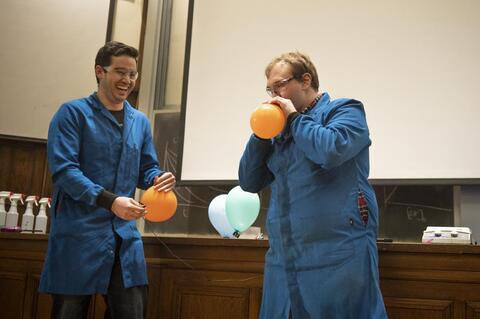 Two men inhaling helium from balloons